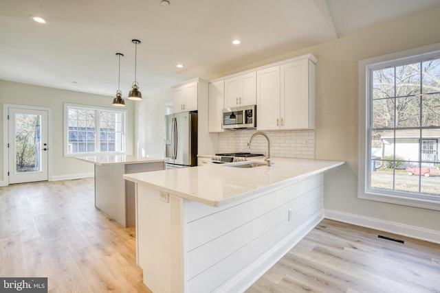 kitchen with plenty of natural light, pendant lighting, appliances with stainless steel finishes, and white cabinetry