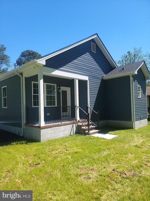 rear view of house featuring a porch and a lawn