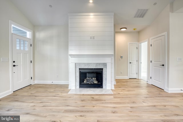 unfurnished living room featuring lofted ceiling, a fireplace, and light hardwood / wood-style flooring