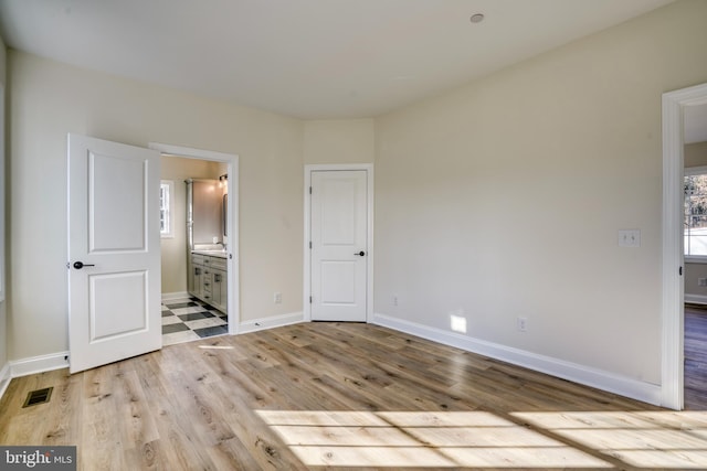 unfurnished bedroom with light hardwood / wood-style flooring and connected bathroom