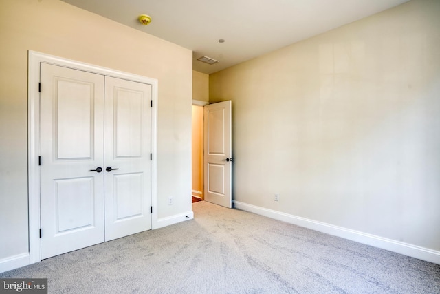 unfurnished bedroom featuring light colored carpet and a closet