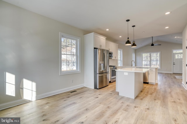 kitchen featuring hanging light fixtures, a center island, vaulted ceiling, stainless steel appliances, and ceiling fan