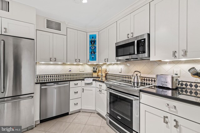 kitchen featuring white cabinets, backsplash, and appliances with stainless steel finishes