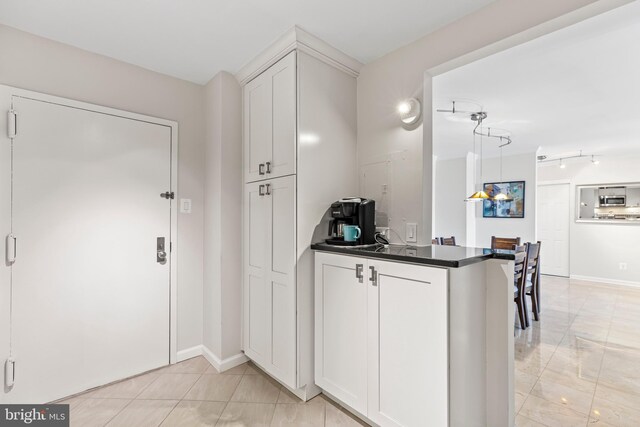 kitchen featuring white cabinets, kitchen peninsula, and decorative light fixtures