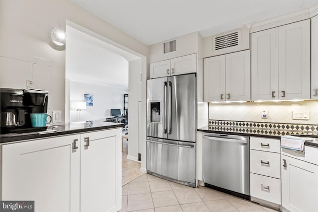 kitchen featuring white cabinets, light tile patterned flooring, stainless steel appliances, and backsplash