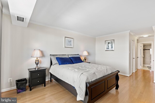 bedroom featuring ensuite bathroom, crown molding, and light hardwood / wood-style floors