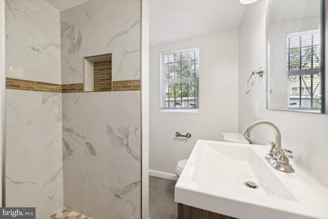 bathroom with vanity, toilet, tiled shower, and tile patterned floors