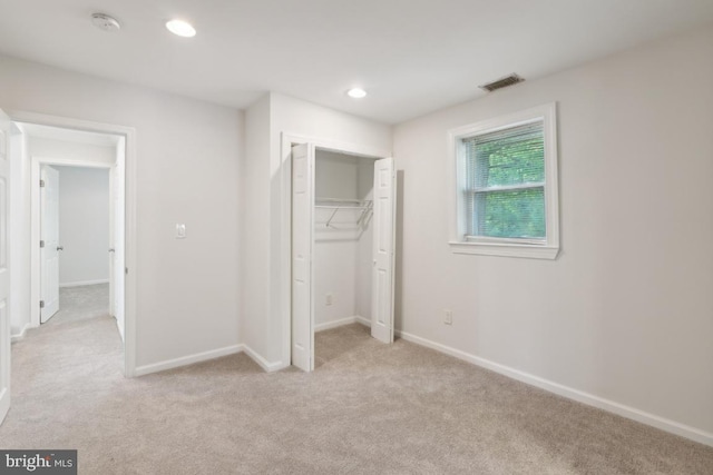 unfurnished bedroom with light carpet and a closet