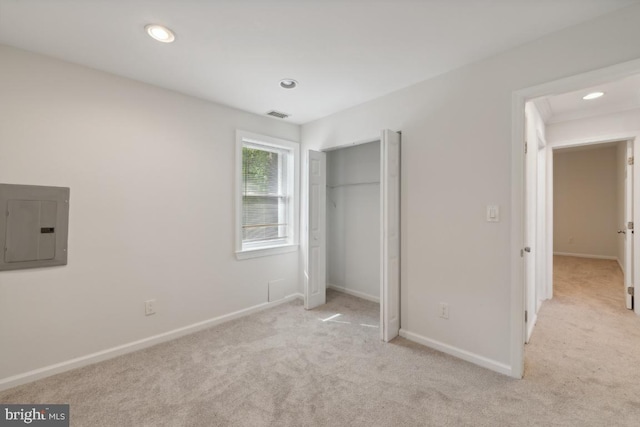 unfurnished bedroom featuring electric panel, light colored carpet, and a closet