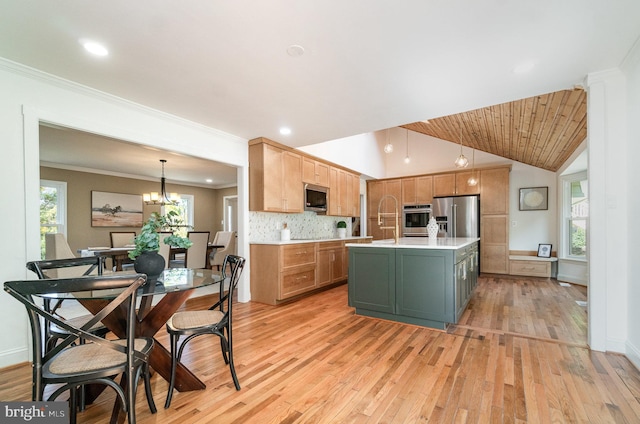 kitchen featuring lofted ceiling, an island with sink, light hardwood / wood-style flooring, decorative light fixtures, and appliances with stainless steel finishes