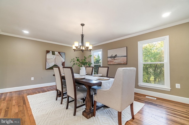 dining area featuring crown molding, wood-type flooring, and an inviting chandelier