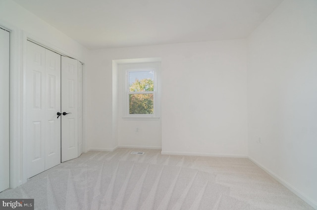 unfurnished bedroom featuring light colored carpet and a closet