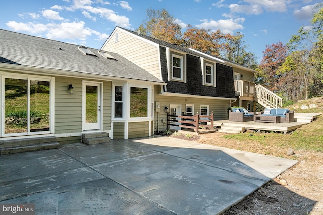 rear view of house with a wooden deck and a patio