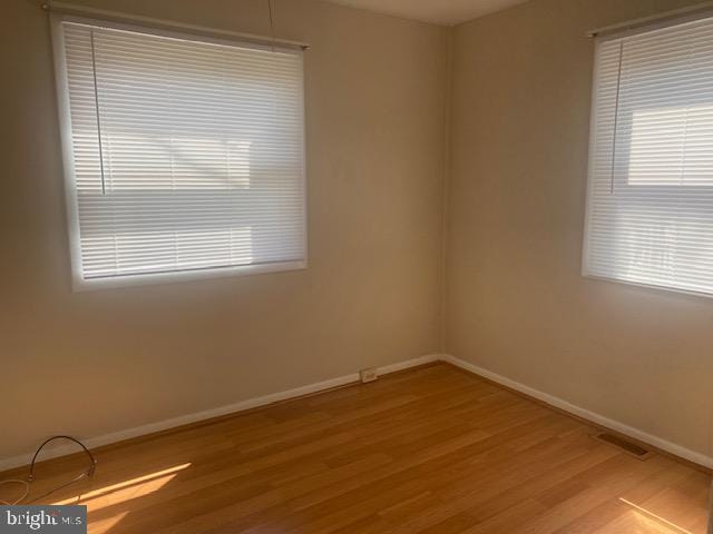 empty room with light hardwood / wood-style flooring and plenty of natural light