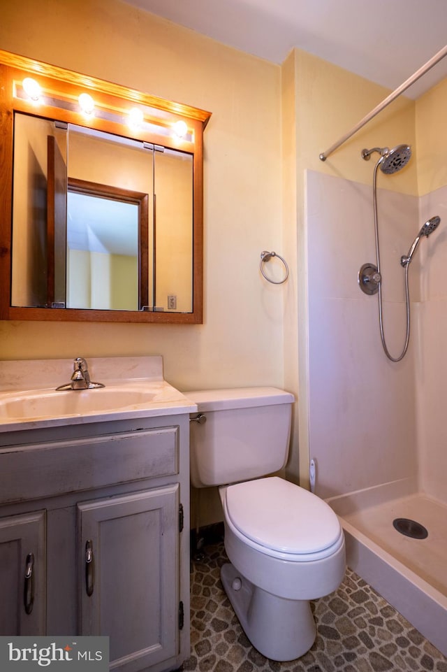 bathroom featuring vanity, toilet, a shower, and tile patterned flooring