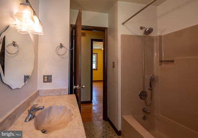 bathroom featuring hardwood / wood-style floors, washtub / shower combination, and vanity