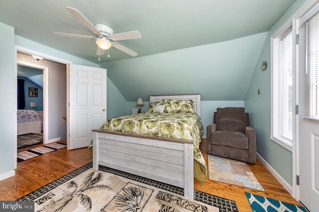 bedroom with a ceiling fan, vaulted ceiling, wood finished floors, and baseboards