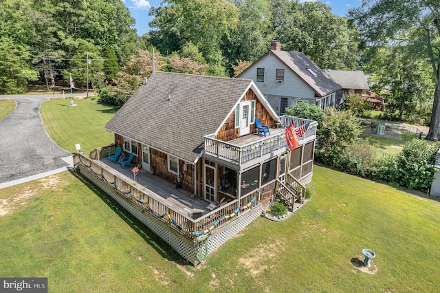 back of house with aphalt driveway, a lawn, a wooden deck, and roof with shingles