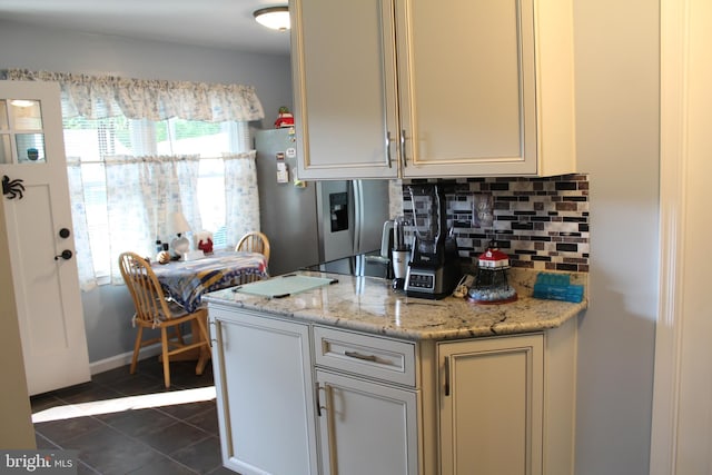 kitchen with dark tile patterned floors, tasteful backsplash, stainless steel fridge with ice dispenser, black electric stovetop, and light stone countertops