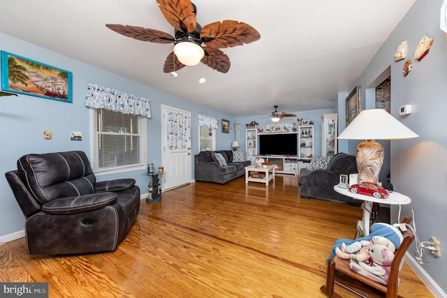 living area featuring a ceiling fan, baseboards, and wood finished floors