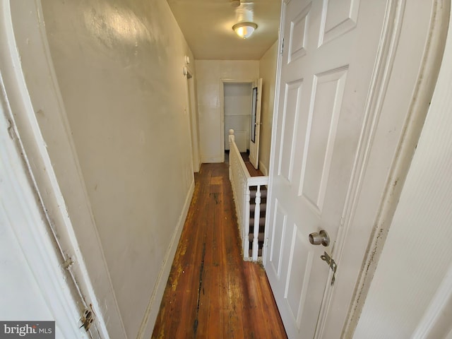 hallway with dark wood-style floors, an upstairs landing, and baseboards