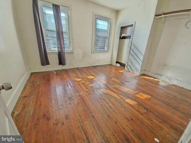 unfurnished bedroom featuring multiple windows and dark hardwood / wood-style flooring