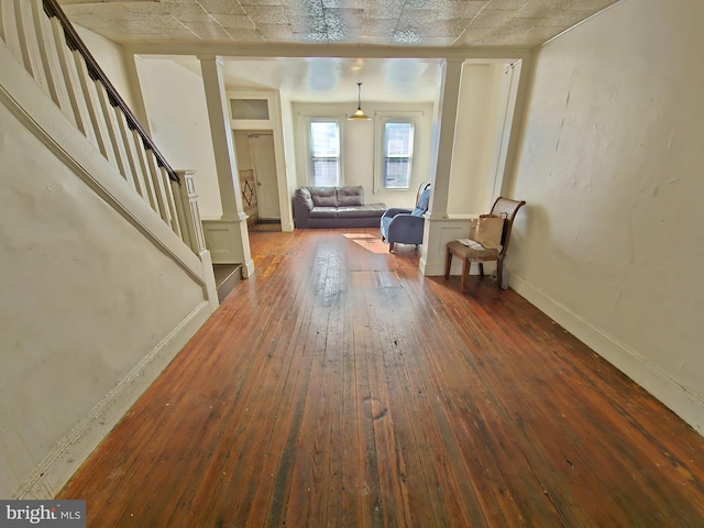 entrance foyer featuring hardwood / wood-style flooring, stairway, baseboards, and ornate columns