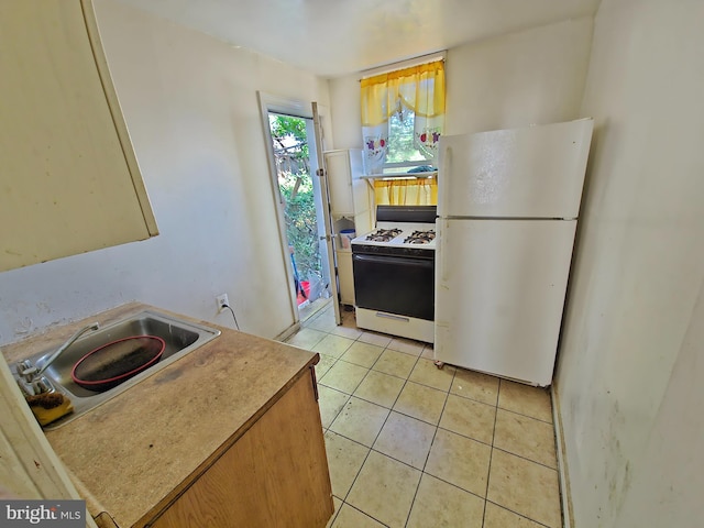 kitchen featuring white appliances, light tile patterned floors, and sink