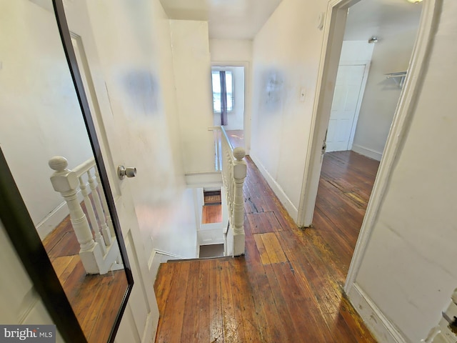 corridor with baseboards, an upstairs landing, and hardwood / wood-style flooring