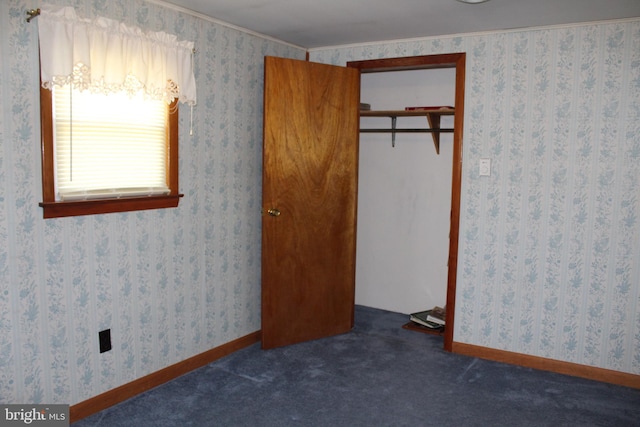 unfurnished bedroom with dark carpet, ornamental molding, and a closet