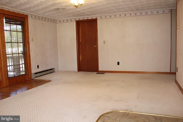 unfurnished room with a baseboard heating unit, baseboards, visible vents, and carpet floors