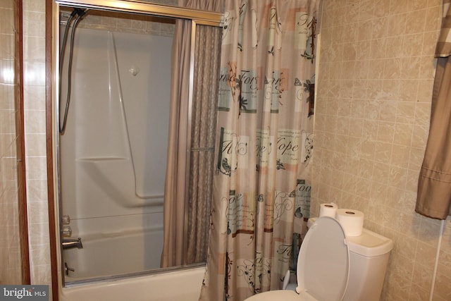 bathroom with shower / tub combo, toilet, and tile walls