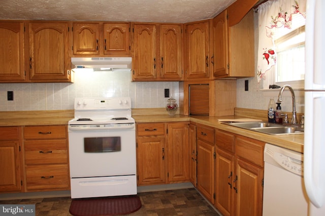 kitchen with under cabinet range hood, light countertops, brown cabinets, white appliances, and a sink