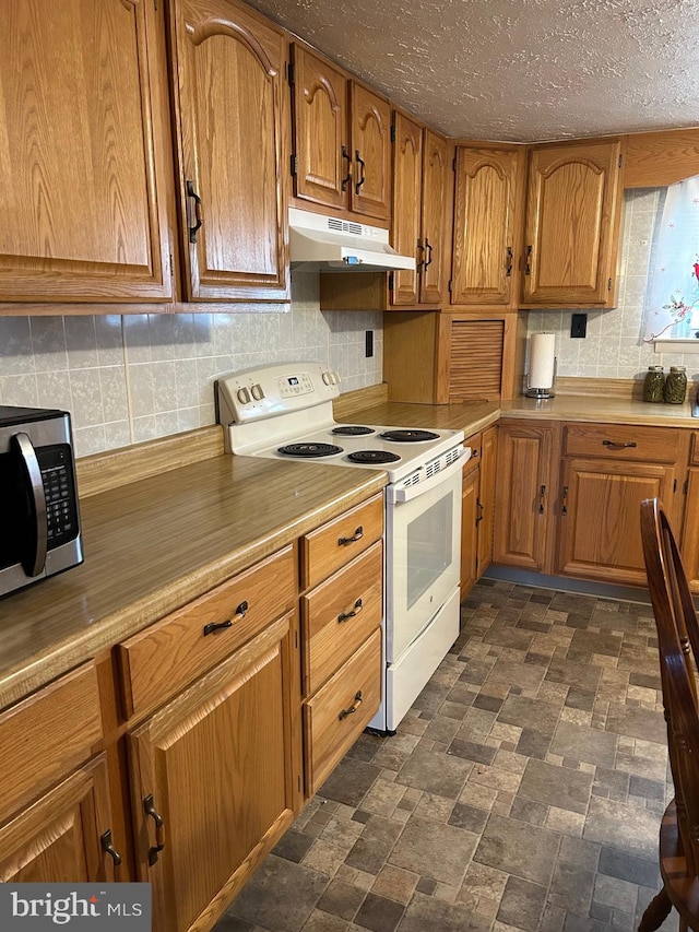 kitchen featuring under cabinet range hood, stainless steel microwave, brown cabinetry, and white electric range