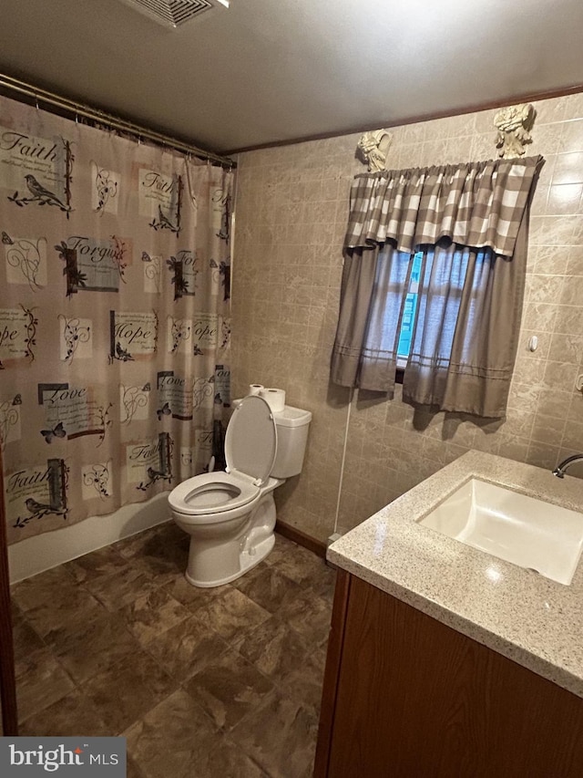 bathroom with visible vents, toilet, vanity, shower / bath combination with curtain, and tile walls