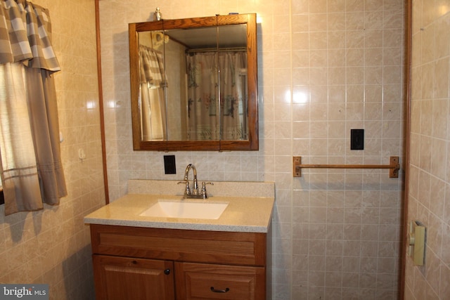 bathroom featuring curtained shower, tile walls, and vanity