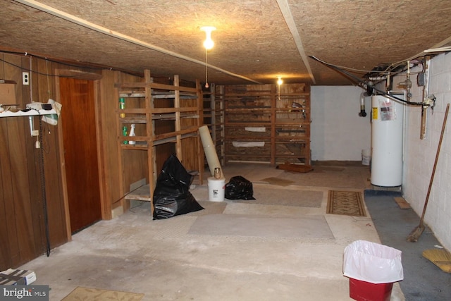 basement featuring wood walls and water heater