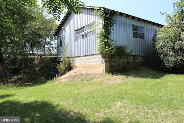 view of home's exterior with a lawn, board and batten siding, and fence