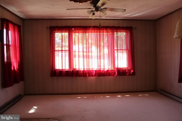 carpeted spare room with a baseboard heating unit, a textured ceiling, and a ceiling fan