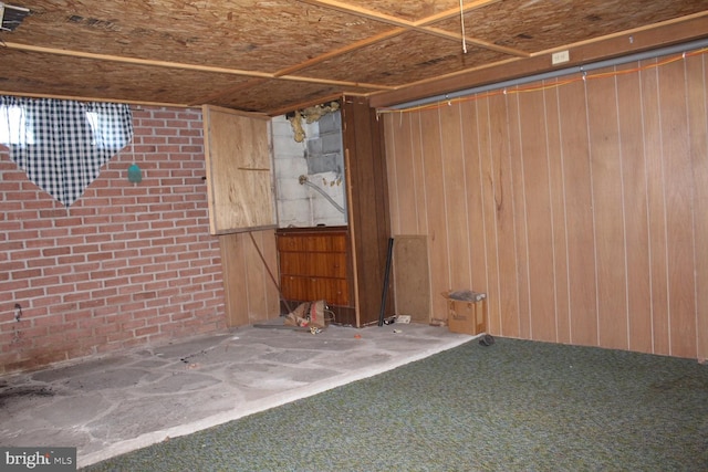 interior space with carpet, wooden walls, and brick wall