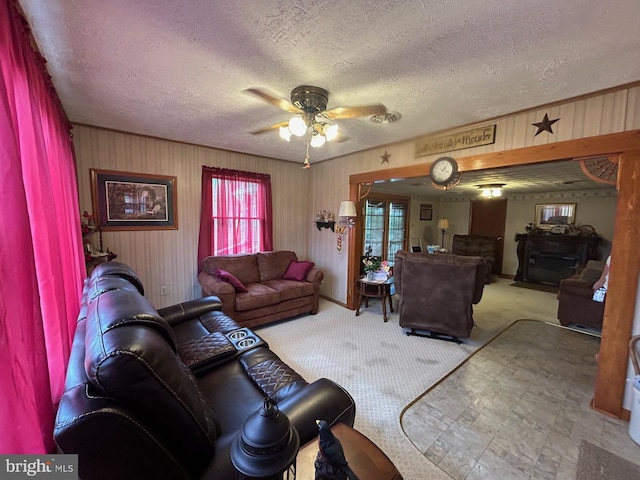 living area featuring carpet, a ceiling fan, and a textured ceiling