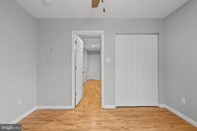 unfurnished bedroom with ceiling fan, electric panel, a closet, and light hardwood / wood-style floors