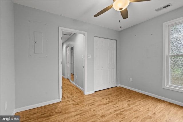 unfurnished bedroom with ceiling fan, electric panel, light wood-type flooring, and a closet