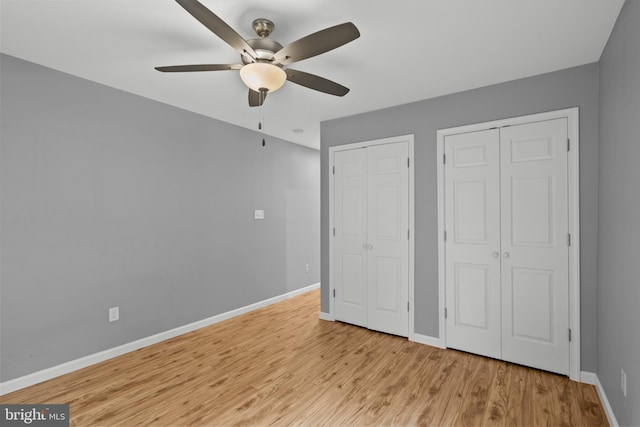 unfurnished bedroom with light hardwood / wood-style floors, two closets, and ceiling fan