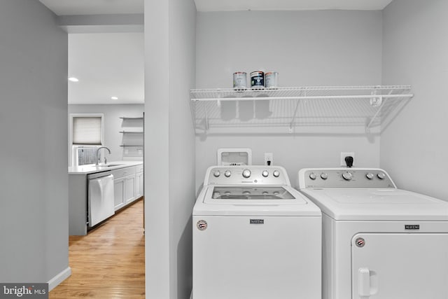 washroom with washer and clothes dryer, light hardwood / wood-style flooring, and sink