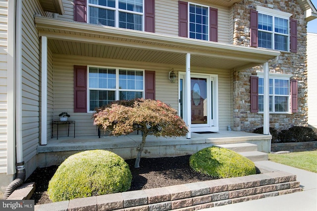 doorway to property with covered porch and stone siding