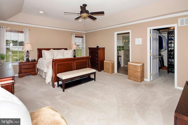 carpeted bedroom with lofted ceiling, ceiling fan, ensuite bath, a tray ceiling, and a walk in closet