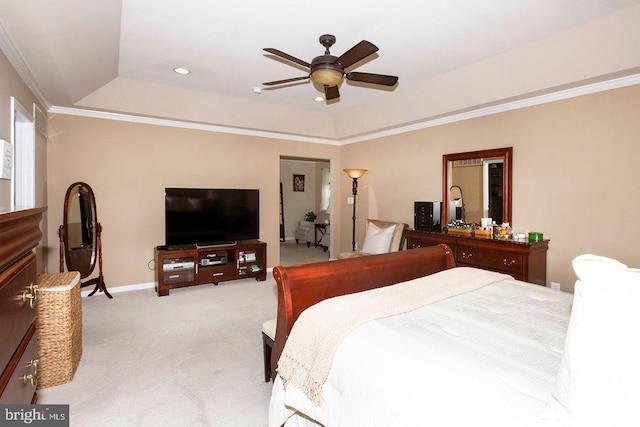 carpeted bedroom with a tray ceiling, crown molding, and ceiling fan