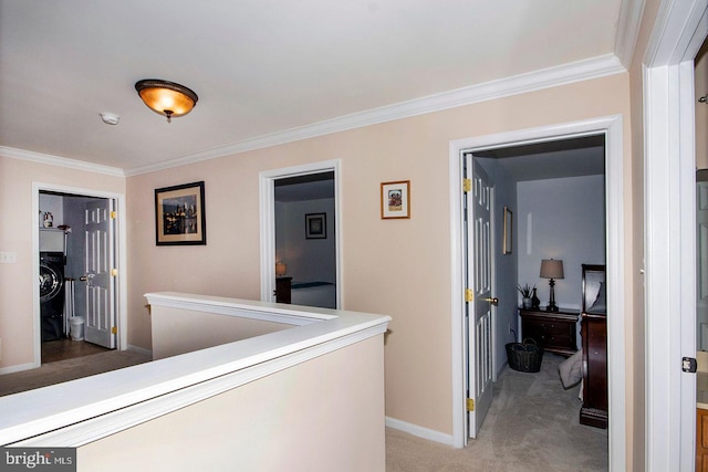 hall featuring an upstairs landing, light carpet, ornamental molding, washer / clothes dryer, and baseboards