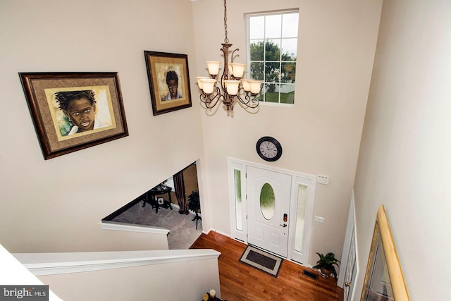 entryway featuring an inviting chandelier, wood finished floors, and a towering ceiling